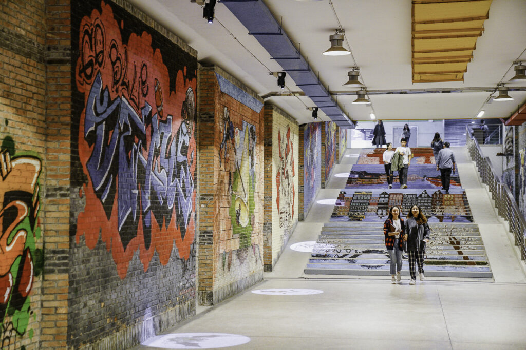 Students walking down a staircase in front of a graffiti mural at Xi’an Jiaotong-Liverpool University.